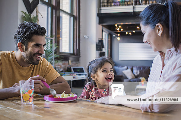 Mother and father feeding their little daughter in kitchen