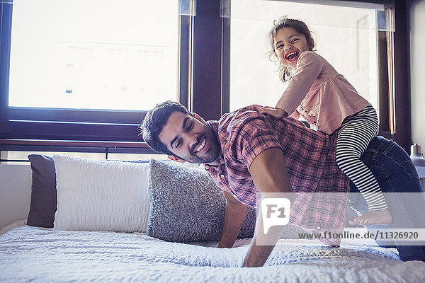 Vater und Tochter spielen auf dem Bett