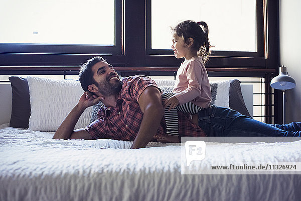 Father and daughter playing on bed