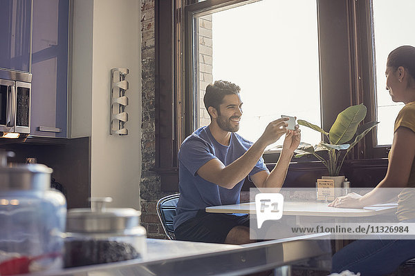 Junges Paar in der Küche beim Fotografieren von Smartphones