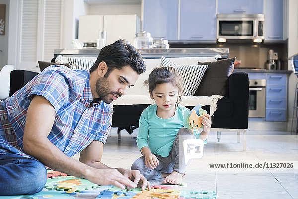 Father and daughter sitting on floor playing with children's puzzle