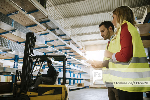 Man and woman wearing reflective vests in warehouse