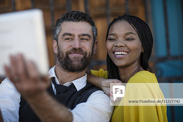 Mann und lächelnde Frau nehmen einen Selfie mit Tablette