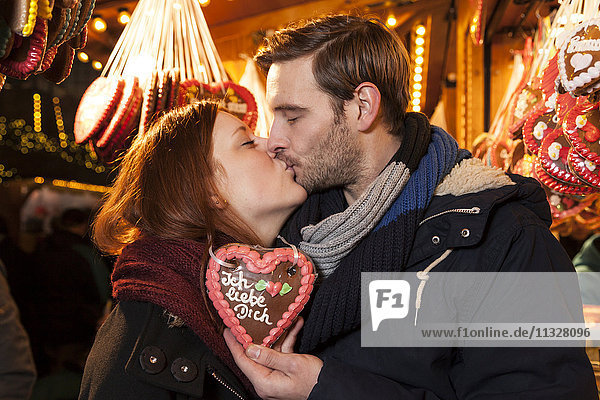 couple kissing on christmas market with german gingerbread heart