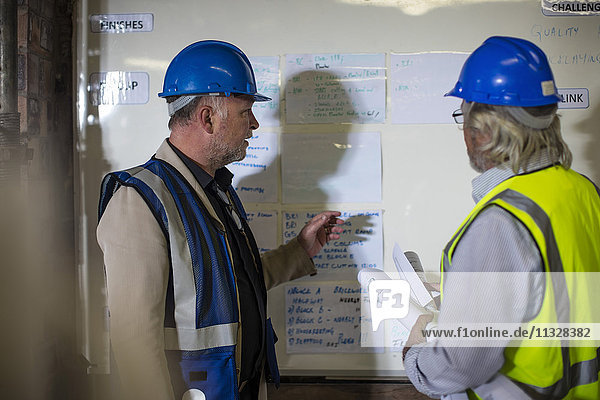 Construction worker and engineer discussing project in site office