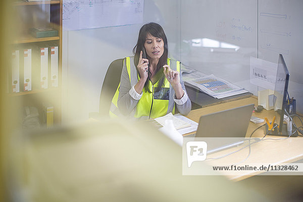 Female construction engineer making a call in site office