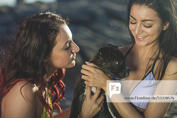 Zwei junge Frauen mit Hund am Strand