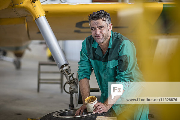 Mechanic in hangar lubricating landing gear of light aircraft