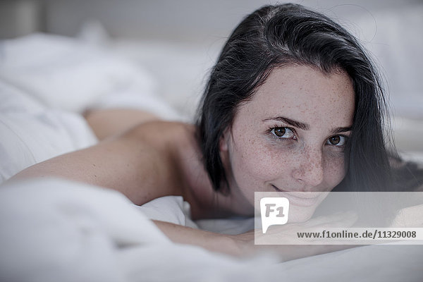 Portrait of smiling young woman lying in bed