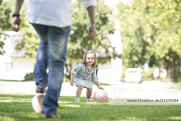 Vater spielt Ball im Garten mit Tochter