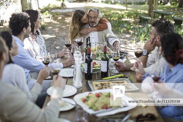 Adult daughter embracing father during lunch in garden