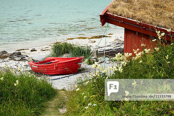 Europa  Norwegen  Lofoten  Insel Flakstadoya  ein rotes Boot neben einem kleinen Haus