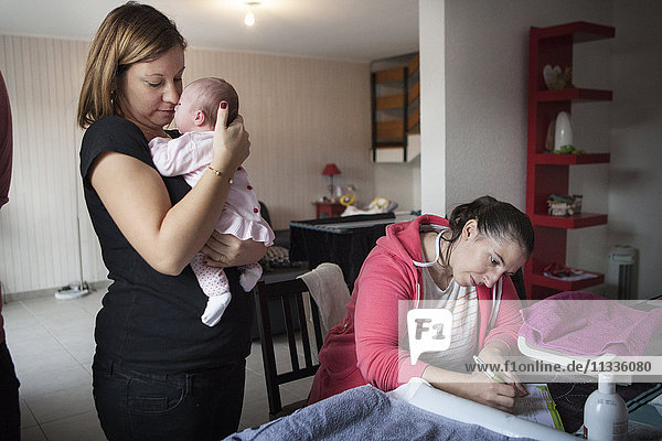 Reportage on an independent midwife during post-partum home visits. The midwife fills in the baby's health records.