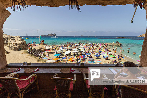 Spanien  Baleareninsel  Ibiza  Strand Cala Comte  Frau sitzt im Cafe
