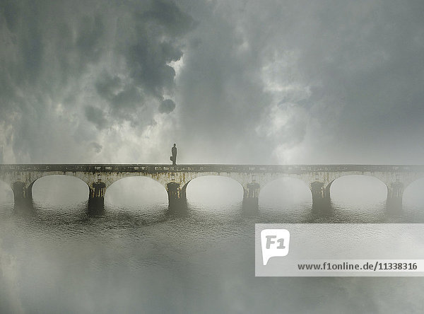 Geschäftsmann steht allein auf einer Brücke im Nebel