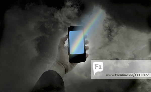 Das Ende des Regenbogens auf einem Smartphone in der Hand eines Mannes