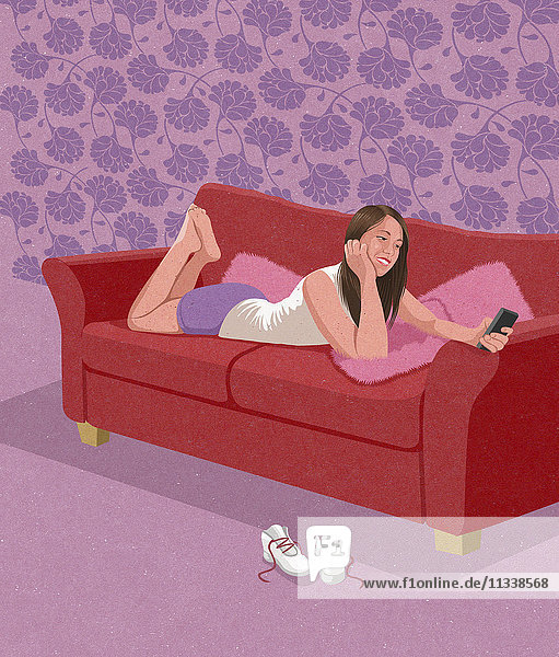 Teenagerin liegt auf der Couch und benutzt ein Handy