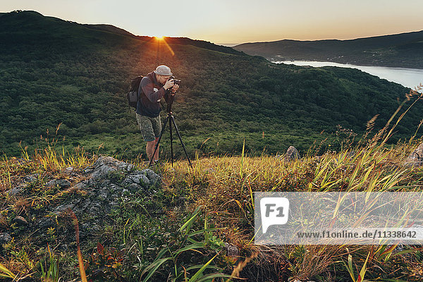 Man photographing on grassy field during sunset