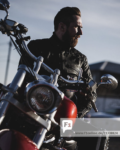 Portrait of biker sitting on motorcycle and looking away