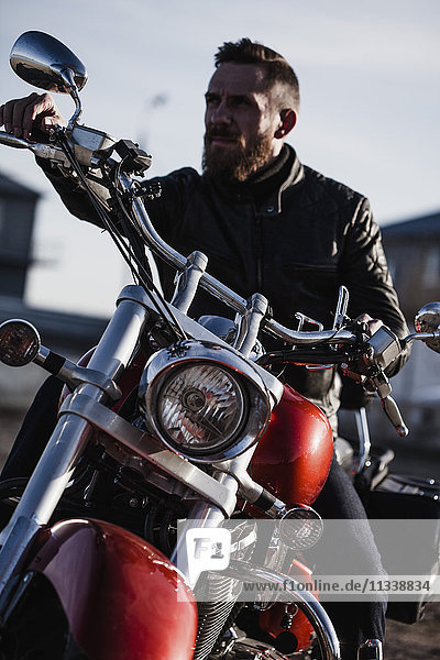 Portrait of biker sitting on motorcycle and looking away