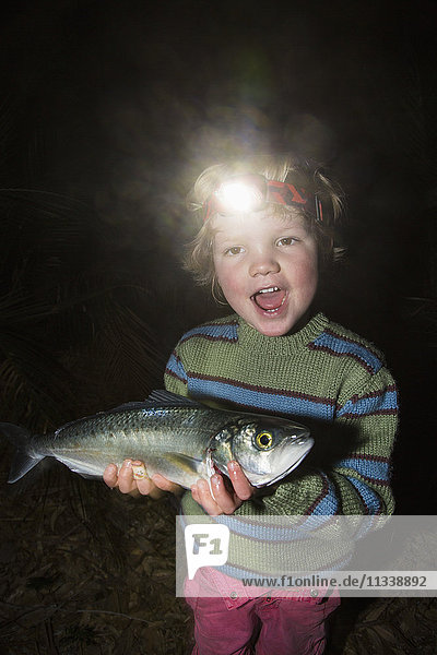Porträt eines fröhlichen Jungen mit Scheinwerferfisch im Wald