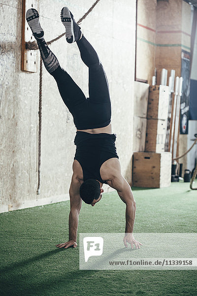 Rear view of sportsman doing handstand in gym