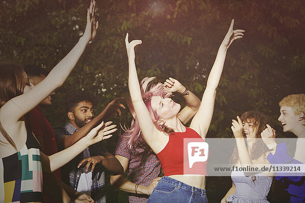 Aufgeregte Frau beim Tanzen mit Freunden auf dem Hof während der Party