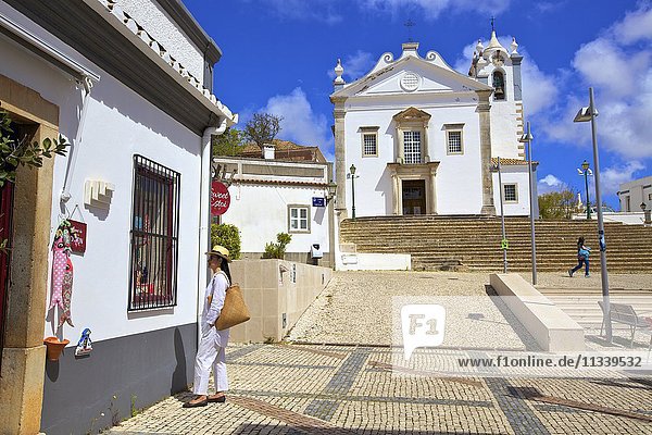 Einkaufen mit der neoklassizistischen Kirche Igreja Matriz de Estoi im Hintergrund  Estoi  Ostalgarve  Algarve  Portugal  Europa
