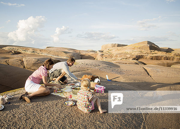 Family enjoying picnic on rock formation against sky