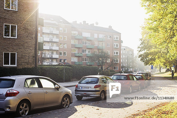 Autos am Straßenrand gegen Mehrfamilienhäuser geparkt