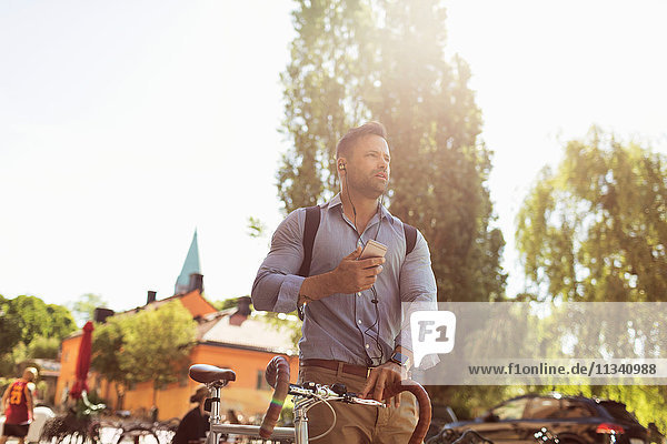 Tiefblick auf den Geschäftsmann mit Fahrrad und Smartphone an einem sonnigen Tag