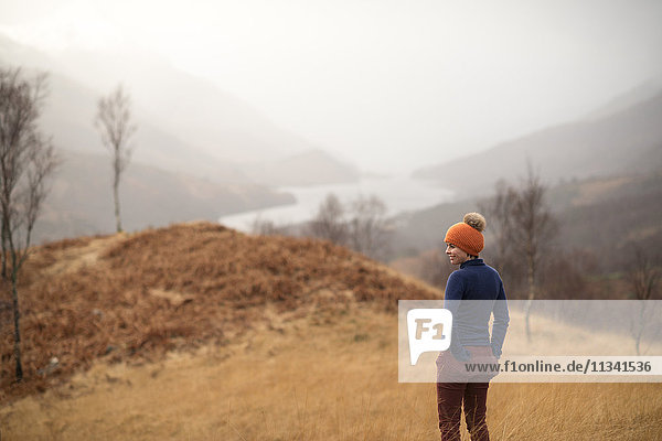 Eine Frau  die in der Nähe von Kinlochlevan spazieren geht  mit dunstigem Blick auf Loch Leven  Perth und Kinross  Highlands  Schottland  Vereinigtes Königreich  Europa