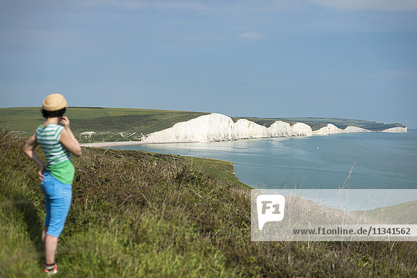 Eine Frau blickt beim Wandern auf dem South Downs Way auf die Seven Sisters  South Downs National Park  East Sussex  England  Vereinigtes Königreich  Europa