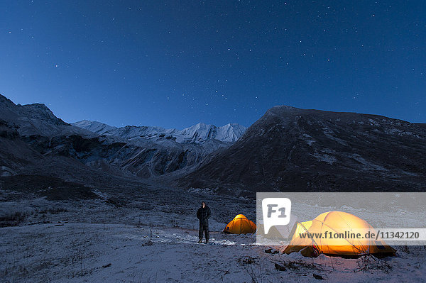 Ein Mann steht in einer kalten Nacht vor seinem Zelt im wenig erforschten Juphal-Tal in der abgelegenen Dolpa-Region  Nepal  Asien