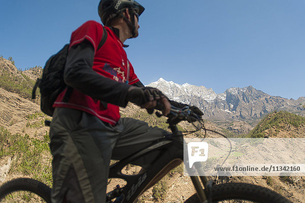 A mountain biker in the Tsum Valley stops to check out the view  Nepal  Asia