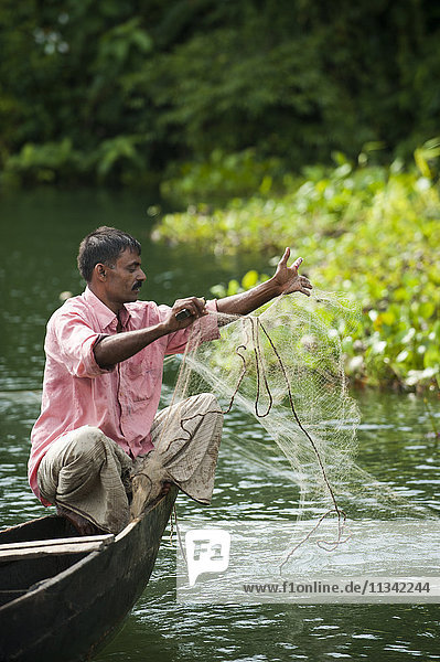 Ein Mann zieht sein Fischernetz am Kaptai-See ein  Chittagong Hill Tracts  Bangladesch  Asien