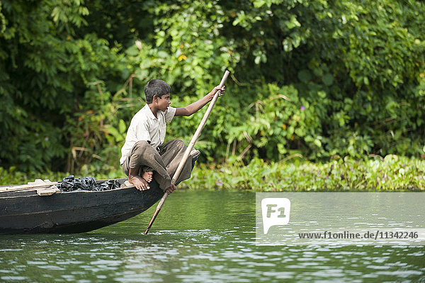 A boy paddles across Kaptai Lake Chittagong Hill Tracts Bangladesh Asia