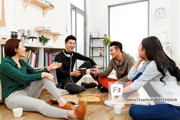 Business men and women eat pizza in the office