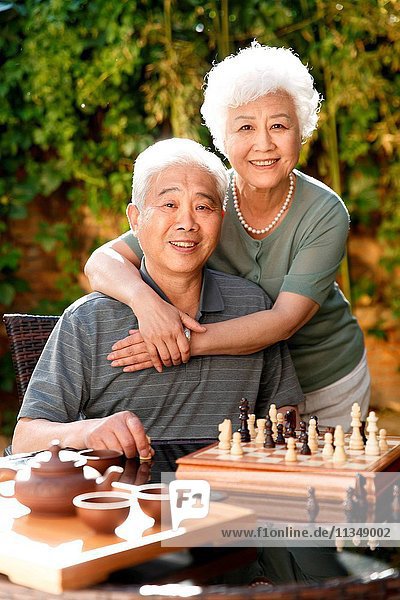 Old couple in the yard to play chess