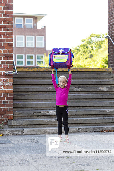 Blond girl holding school bag aloft  Kiel  Schleswig-Holstein  Germany  Europe