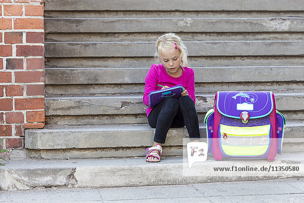 Blond girl sitting with school bag on stairs  Kiel  Schleswig-Holstein  Germany  Europe