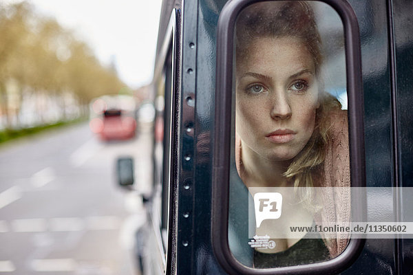 Serious young woman behind car window looking out