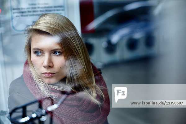 Junge Frau hinter einer Fensterscheibe