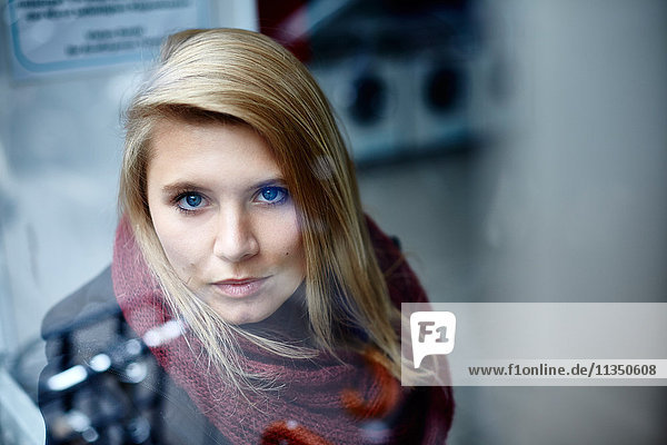 Portrait of young woman behind window pane