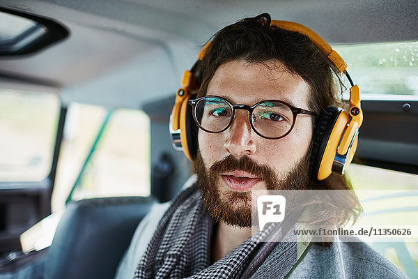 Portrait of bearded man in car wearing headphones