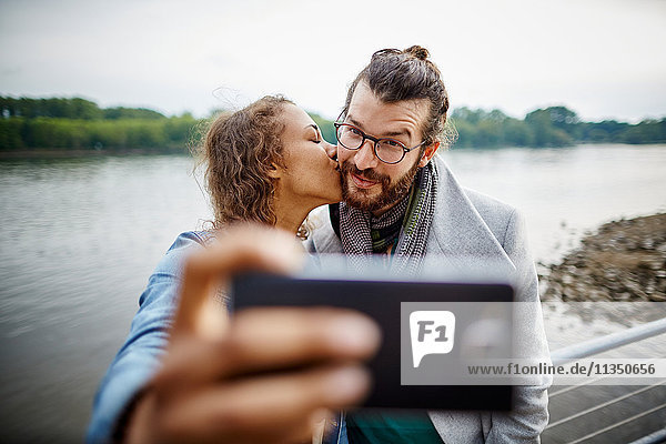 Junges Paar macht ein Selfie am Flussufer
