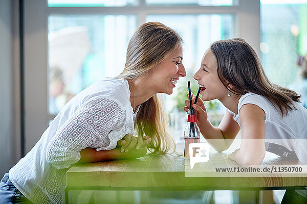 Glückliche Mutter und Tochter teilen sich ein Erfrischungsgetränk im Restaurant