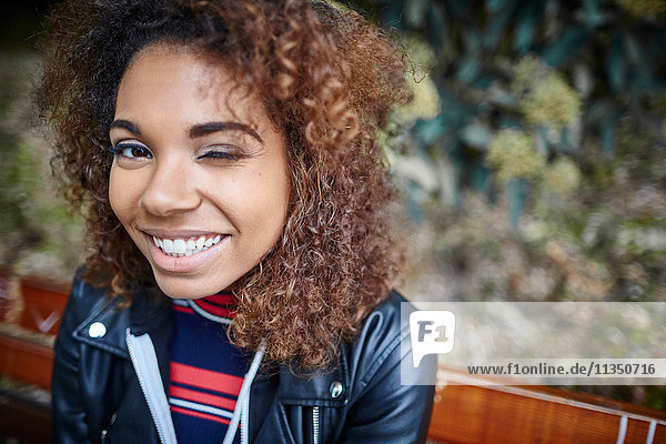 Portrait of smiling young woman on park bench