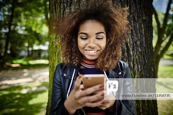 Glückliche junge Frau schaut auf ihr Handy