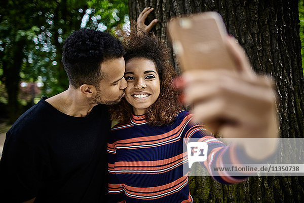 Smiling young couple on park bench taking a selfie